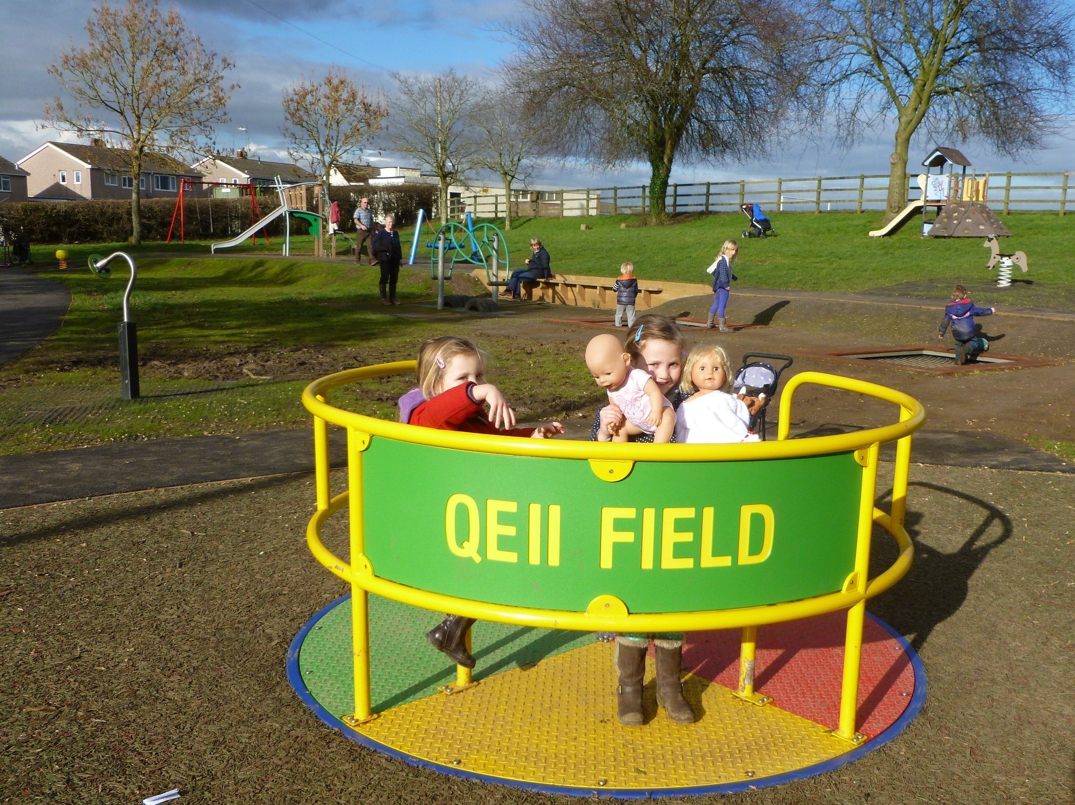 Children enjoying the Childrens roundabout, named QE 2 Field, in the play area in King George the fifth park