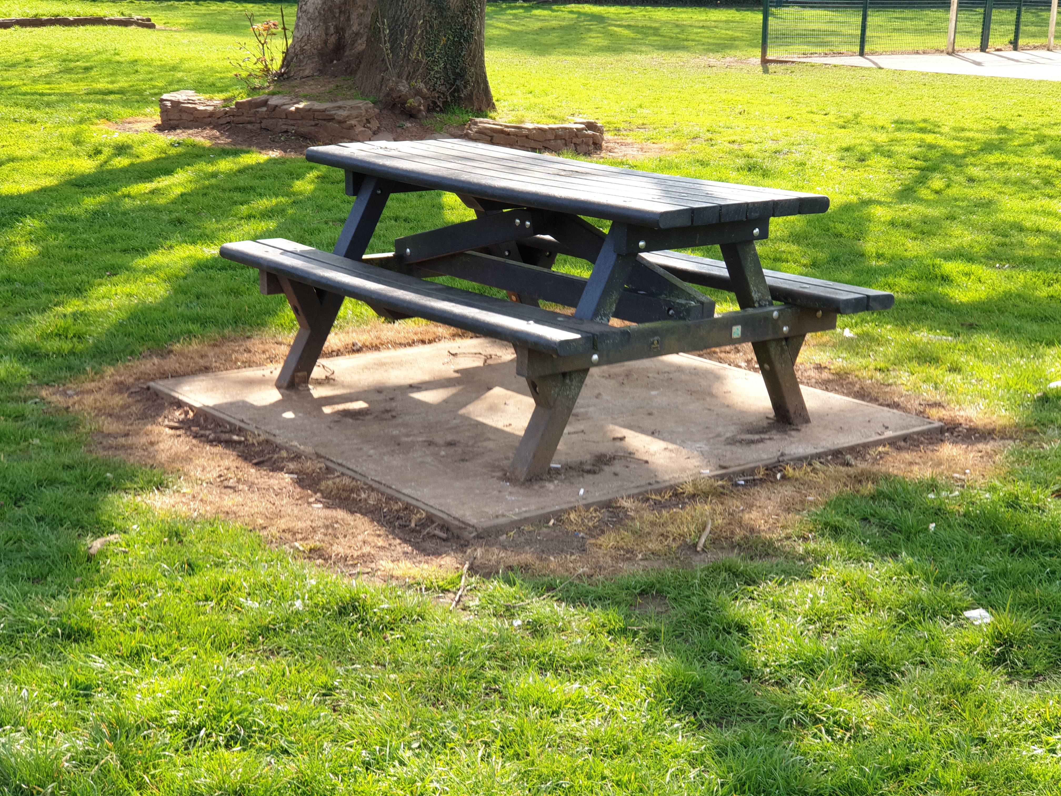 The picnic table between the basketball court and the childrens play area.