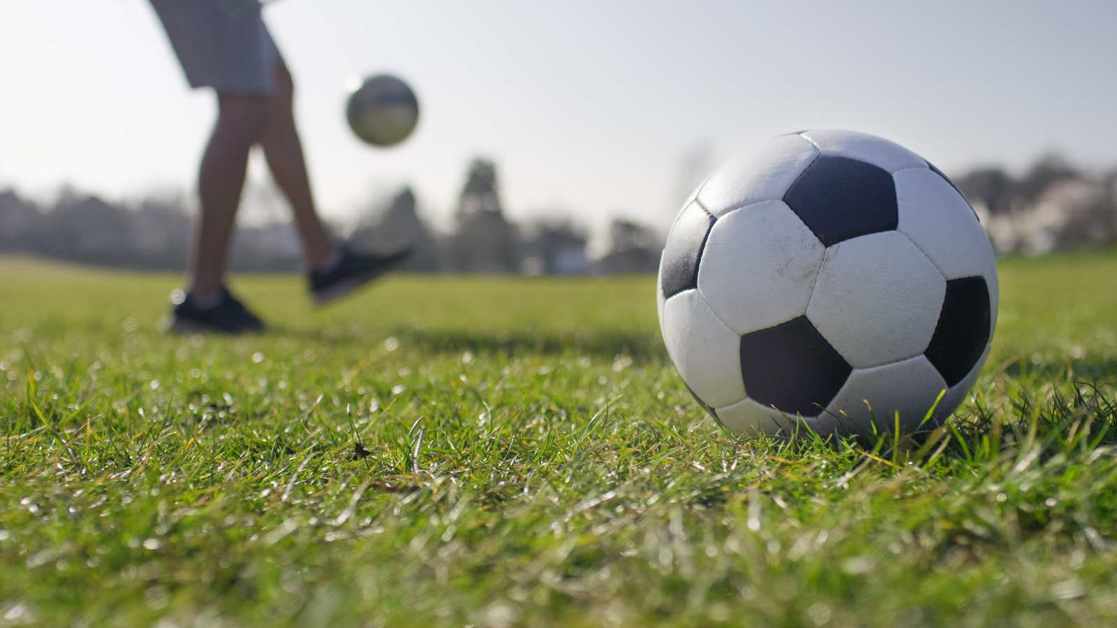 Ground level view of a football and a child kicking another ball 